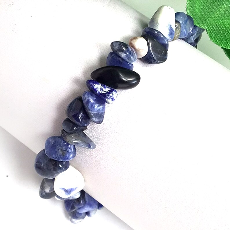May include: A blue and white gemstone bracelet made of small, irregular shaped stones. The bracelet is made of natural stones and is a beautiful and unique piece of jewelry.