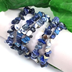 May include: A multi-strand bracelet made of blue and white chipped lapis lazuli stones. The bracelet is made of several strands of stones that are knotted together.