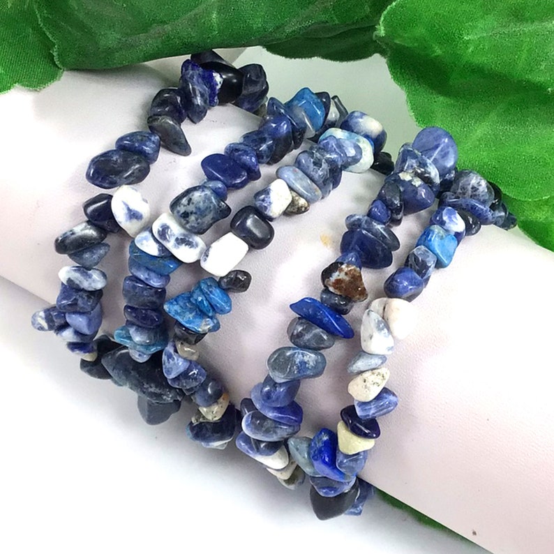May include: A multi-strand bracelet made of blue and white chipped lapis lazuli stones. The bracelet is made of several strands of stones that are knotted together.
