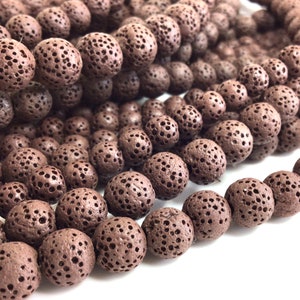 May include: A strand of brown lava rock beads. The beads are round and have a porous texture.