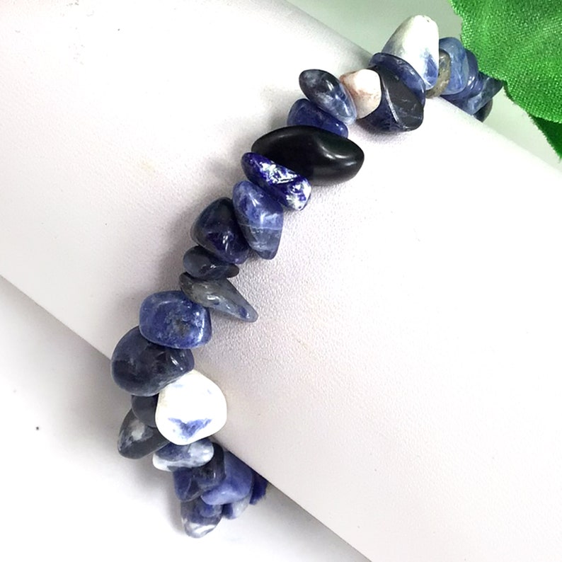 May include: A blue and white gemstone bracelet made of small, irregular shaped stones. The bracelet is made of natural stones and is a beautiful and unique piece of jewelry.