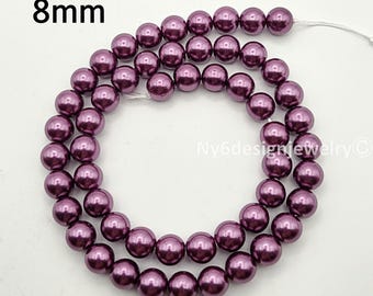 May include: A strand of deep purple, 8mm beads. The beads are round and have a glossy finish. The text "8mm" is in the upper left corner. The beads are strung on a white string, ready for jewelry making. The background is white.