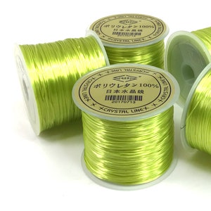 May include: Four spools of bright green elastic thread. Each spool has a gold label with Japanese text that reads "Polyurethane 100% Japanese Crystal Line" and a date code.
