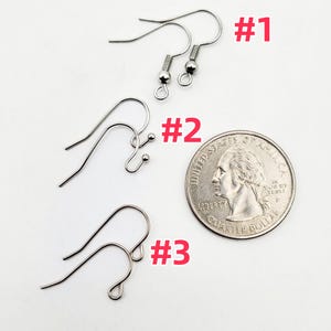 May include: Close-up of three different styles of silver-colored earring hooks. The hooks are displayed next to a US quarter for size comparison. The image is on a white background. The hooks are labeled #1, #2, and #3 in red.