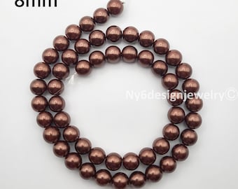 May include: A strand of 8mm brown beads. The beads are a rich, dark brown color and appear to be round and smooth. The beads are strung on a white string, ready for jewelry making. The text "8mm" is in the upper left corner.