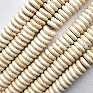 May include: Close-up of strands of off-white, disc-shaped beads. The beads have a slightly irregular shape and a marbled appearance with brown veining. The beads are strung together, creating a textured surface. Ideal for jewelry making.