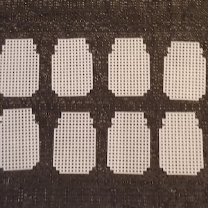 May include: Eight white plastic canvas circles, each with a grid pattern, are arranged in two rows of four on a dark gray textured surface.