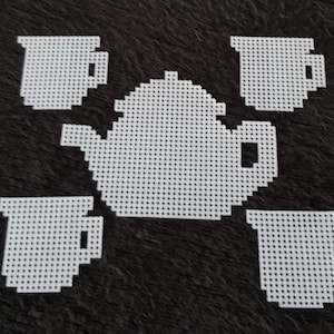 May include: White crocheted tea set with a teapot and four cups. The set is made of white yarn and has a simple design.