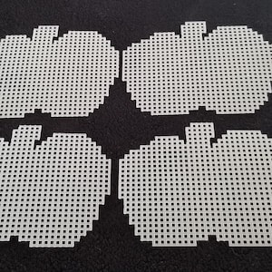 May include: Four white plastic pumpkin shapes with a grid-like pattern, perfect for crafting. The pumpkins are arranged on a dark background. Each pumpkin has a stem and a rounded body, ideal for various DIY projects.