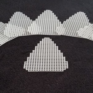 May include: A set of ten white plastic canvas triangles, perfect for crafting projects. The triangles are arranged in a semi-circle shape, with the largest triangle in the center.