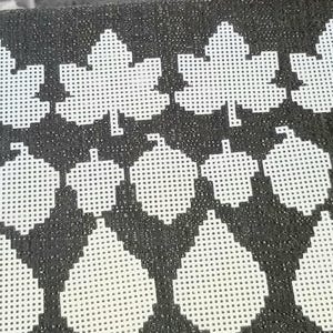 May include: White plastic canvas cutouts in the shapes of maple leaves, acorns, and teardrops are arranged on a dark gray textured surface. The shapes are evenly spaced, creating a pattern suitable for crafting projects.
