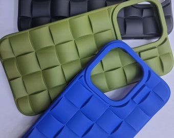 May include: Three phone cases in different colors: black, green, and blue. The cases have a quilted design and a cutout for the camera lens.