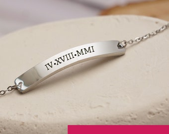 May include: Silver bracelet with a curved bar engraved with the Roman numeral date "IV.XVIII.MMI".