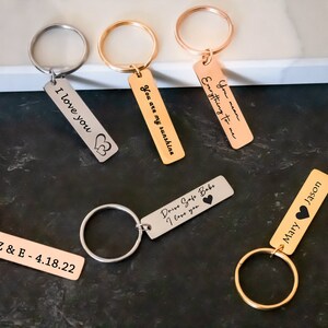 K&ouml;nnte beinhalten: Ein Set aus sechs Schl&uuml;sselanh&auml;ngern in Silber und Gold mit gravierten Botschaften. Die Botschaften lauten: "Ich liebe dich", "Du bist mein Sonnenschein", "Alles f&uuml;r mich", "Fahr vorsichtig mein Schatz ich liebe dich", "Z & E - 4.18.22" und "Mary Jason".
