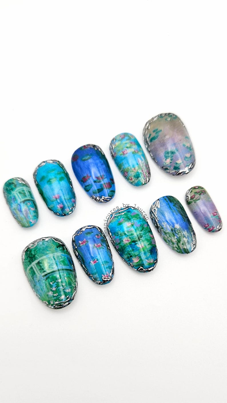 May include: A set of ten artificial nails with a water lily design. Each nail features a different section of a water lily pond, with blue, green, and purple hues. The nails are outlined with a silver metallic trim.