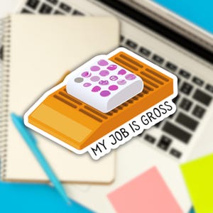 Może przedstawiać: Naklejka z białym kwadratem z różowymi kółkami na żółtej rampie. Na naklejce widnieje napis "MY JOB IS GROSS".