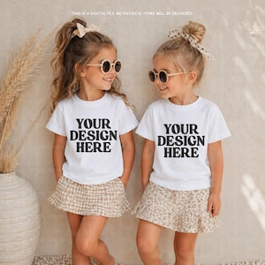 Könnte beinhalten: Zwei junge Mädchen tragen weiße T-Shirts mit dem schwarzen Text "YOUR DESIGN HERE", kombiniert mit Röcken und Sonnenbrillen. Ein Rock ist kariert, der andere floral. Der Text im Bild lautet: "THIS IS A DIGITAL FILE. NO PHYSICAL ITEMS WILL BE DELIVERED."