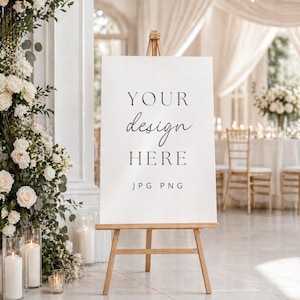 May include: A white rectangular sign displayed on a light brown wooden tripod easel. The sign features black text that reads YOUR design HERE and JPG PNG. The sign is positioned in a bright, neutral-toned room with soft lighting and decor.