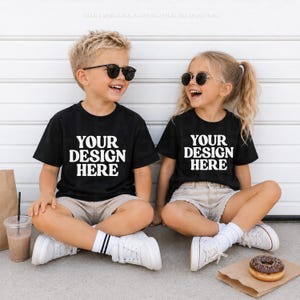 Könnte beinhalten: Zwei schwarze T-Shirts mit dem weißen Text YOUR DESIGN HERE auf der Vorderseite. Die T-Shirts werden mit beigen Shorts und weißen Turnschuhen getragen. Der Text THIS IS A DIGITAL FILE NO PHYSICAL ITEMS WILL BE DELIVERED ist oben sichtbar.
