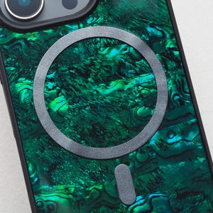 May include: A close-up of a smartphone case with a vibrant green and blue marbled design. The case has a black border and a silver-colored circular accent. The camera lenses are visible at the top. The overall aesthetic is modern and stylish.