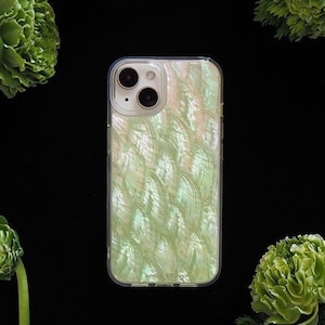 May include: A clear phone case with a green and white iridescent pattern. The case is on a black background with green flowers.