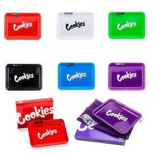 May include: A set of nine rolling trays with the word "Cookies" printed on them. The trays are in various colors, including red, white, green, blue, black, and purple. Some trays are in a box, while others are on a table.