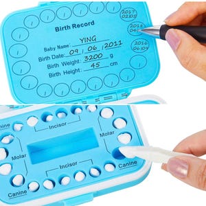 May include: A blue plastic baby tooth storage box with a white lid. The box has a chart for recording the baby's birth information, including name, date, weight, and height. The box also has a chart for tracking the baby's teeth, with spaces for each tooth. The box is open and the lid is flipped over. The box is labeled "Birth Record".