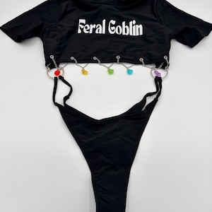 Body con dije de duende salvaje: bañador de fiesta de una pieza elástico con espalda descubierta y dije de cadena arcoíris.