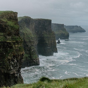 May include: A view of the Cliffs of Moher in Ireland, a dramatic landscape of towering cliffs along the rugged coastline. The cliffs are a popular tourist destination and offer stunning views of the Atlantic Ocean.
