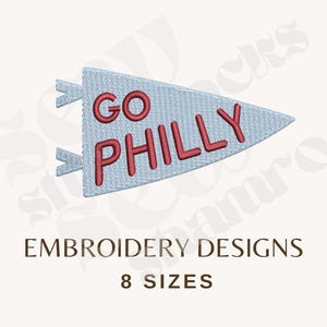 May include: An embroidery design featuring a light blue triangular pennant with two small tabs on the left side. The text GO PHILLY is stitched in red in the center of the pennant. Below the design, the text EMBROIDERY DESIGNS 8 SIZES appears.