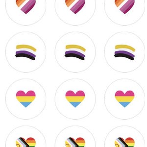 Op de afbeelding: Een verzameling witte ronde stickers met verschillende LGBTQ+ pride-symbolen. Ontwerpen omvatten regenboogbogen, harten met lesbische pride-kleuren, non-binaire vlaggen, panseksuele harten en harten met de progress pride-vlag.