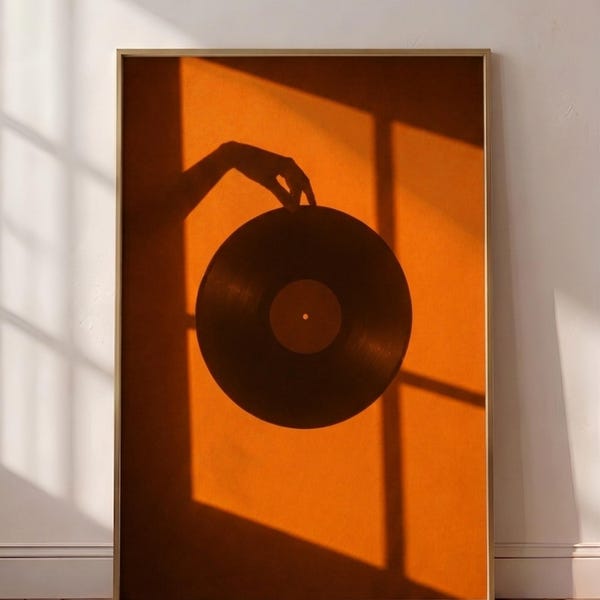 Pode incluir: Uma impressão de arte de parede retangular emoldurada com um fundo laranja vibrante e a silhueta escura de uma mão segurando um disco de vinil circular. A composição inclui sombras geométricas nítidas de uma moldura de janela.