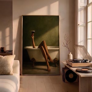 May include: A framed wall art print depicting a person with legs extended out of a white clawfoot bathtub against a dark olive green background. One arm is raised, holding a dark cocktail glass. The artwork is displayed in a living room setting.