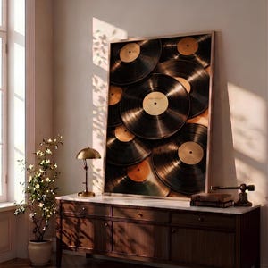 May include: A rectangular framed wall art piece featuring a collage of overlapping black vinyl records with gold center labels. The artwork is displayed on a dark wood sideboard with a white marble top, positioned against a light-colored wall.