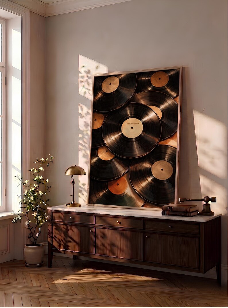 May include: A rectangular framed wall art piece featuring a collage of overlapping black vinyl records with gold center labels. The artwork is displayed on a dark wood sideboard with a white marble top, positioned against a light-colored wall.
