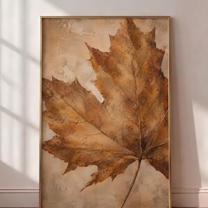 Peut inclure: Une œuvre d'art murale rectangulaire encadrée représentant une grande illustration détaillée d'une feuille d'érable dans des tons de brun, de beige et d'ocre. La feuille est centrée sur un fond texturé aux tons neutres, dans un cadre doré fin.