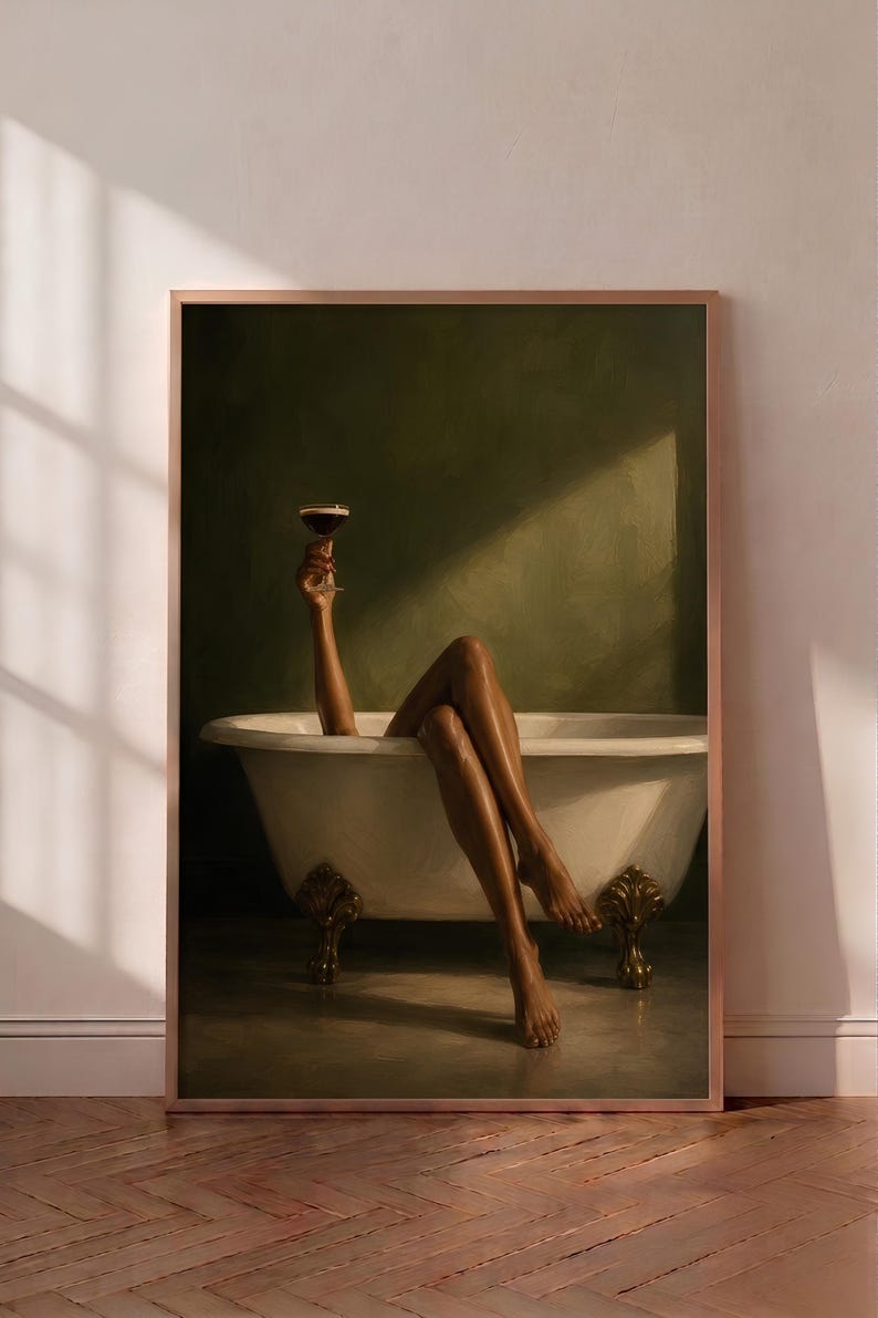 May include: A framed wall art print depicting a white clawfoot bathtub with gold-toned feet against a dark olive green wall. A pair of legs and an arm holding a stemmed cocktail glass are visible, with light casting a diagonal shadow across the scene.