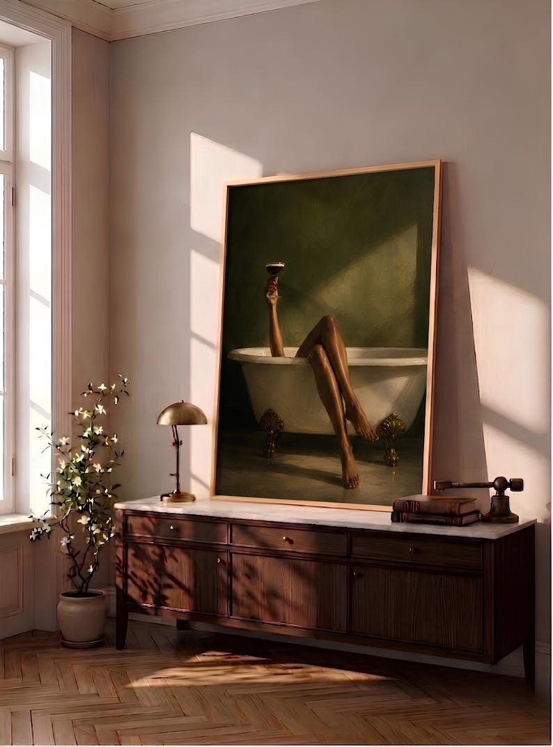 May include: A framed vertical wall art print depicting a person with legs extended out of a white clawfoot bathtub, holding a dark cocktail glass aloft. The background is a solid dark olive green, and the tub features ornate gold-toned feet.