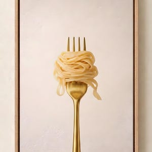 May include: A framed art print featuring a golden fork with a swirl of cooked pasta. The pasta is a light beige color, and the fork has a simple, elegant design. The frame is made of light-colored wood.