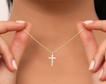 May include: A gold chain necklace with a small, diamond-encrusted cross pendant.
