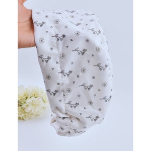 Peut inclure: Bandeau en tissu blanc avec un petit motif floral gris. Le bandeau est rassemblé et plissé.