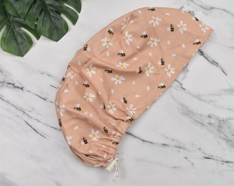 May include: A pink surgical scrub hat with a white daisy and bee pattern.