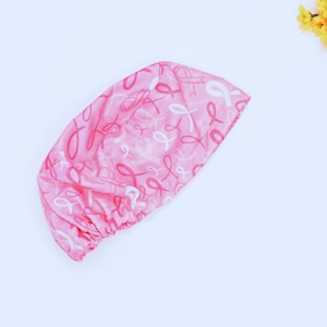 May include: Pink scrub cap with a pattern of pink and white ribbons. The cap is made of a soft fabric and is designed to cover the hair during medical procedures. The ribbons are a symbol of breast cancer awareness.