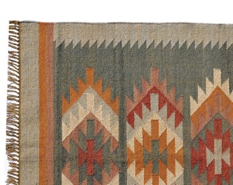 May include: A geometric patterned rug with a fringe border. The rug features a mix of brown, orange, red, and gray colors.