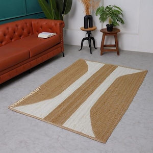 May include: A rectangular area rug featuring a woven natural jute texture with a geometric pattern of wide white stripes and tan jute sections. The text SHEKHAWATIHANDICRAFT is printed in white along the left edge of the rug surface.