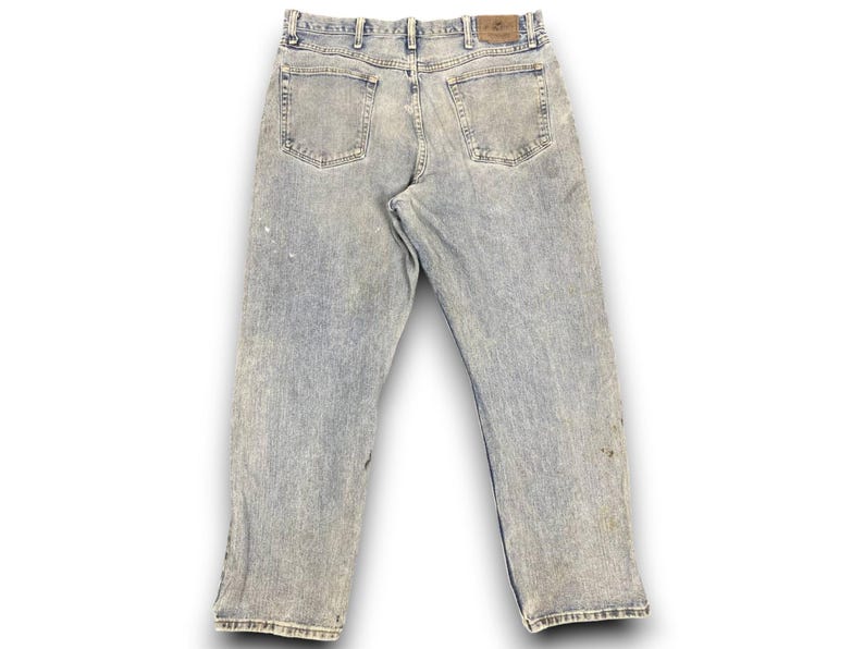 K&ouml;nnte beinhalten: Hellblaue Jeans aus Denim mit einem verwaschenen Effekt. Die Jeans haben ein klassisches F&uuml;nf-Taschen-Design, G&uuml;rtelschlaufen und einen Lederaufn&auml;her auf der R&uuml;ckseite. Die Jeans sind leicht abgenutzt mit Farbflecken.