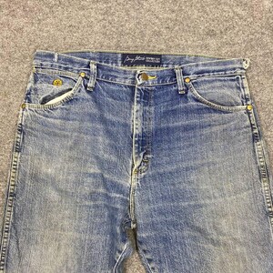 May include: Blue denim jeans with a classic five-pocket design. The jeans feature a button and zipper closure, belt loops, and brass-colored rivets. The "Cowboy Cut Collection" label is visible on the waistband. The jeans have a faded wash and a straight leg.
