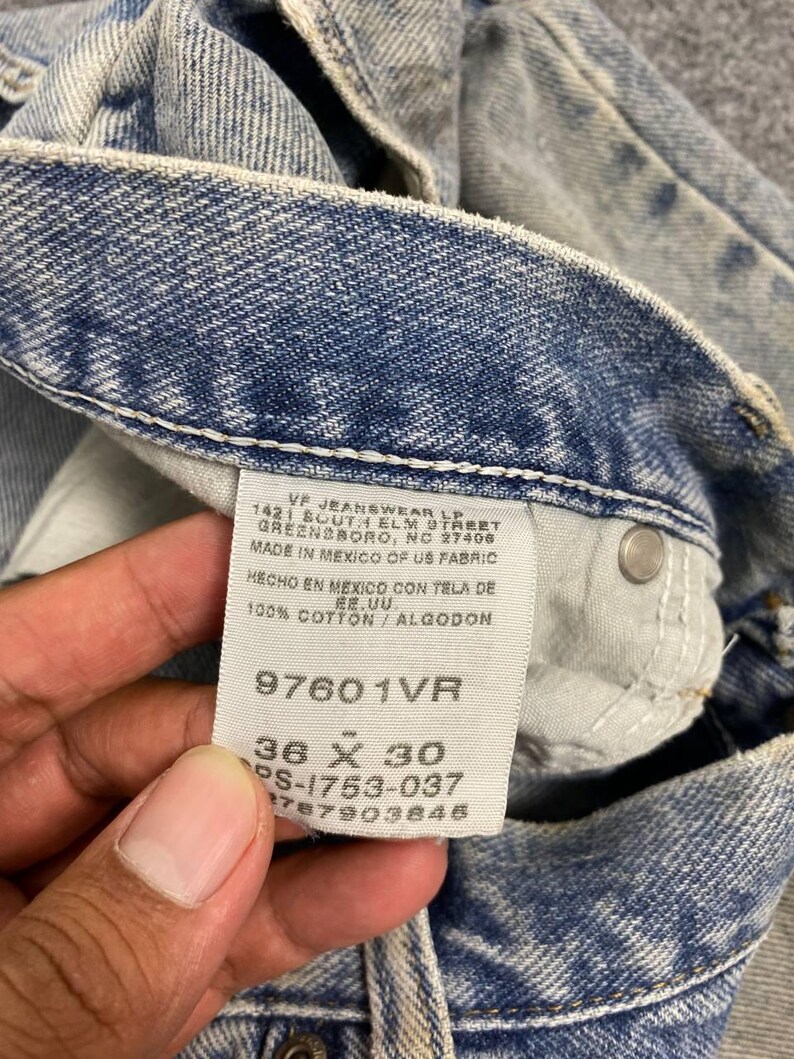 K&ouml;nnte beinhalten: Nahaufnahme eines hellblauen Jeans-Etiketts. Das Etikett lautet "VF JEANSWEAR LP" und enth&auml;lt die Gr&ouml;&szlig;e "36 x 30". Die Jeans besteht aus 100% Baumwolle.
