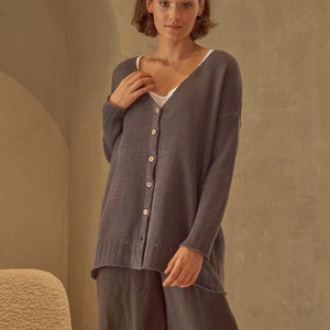 Puede incluir: Un cárdigan de punto gris carbón con cuello en V y cierre de botones. El cárdigan tiene un corte holgado y una longitud ligeramente más larga.