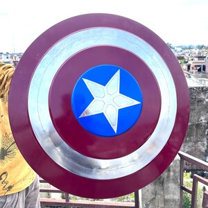 Pu&ograve; includere: Uno scudo di Capitan America rosso, bianco e blu con un bordo argentato. Lo scudo ha una stella a cinque punte al centro.